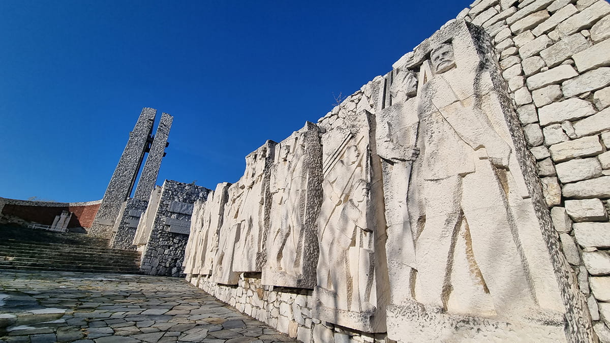 Stone relief figures along the wall of a Bulgarian socialist-era memorial complex